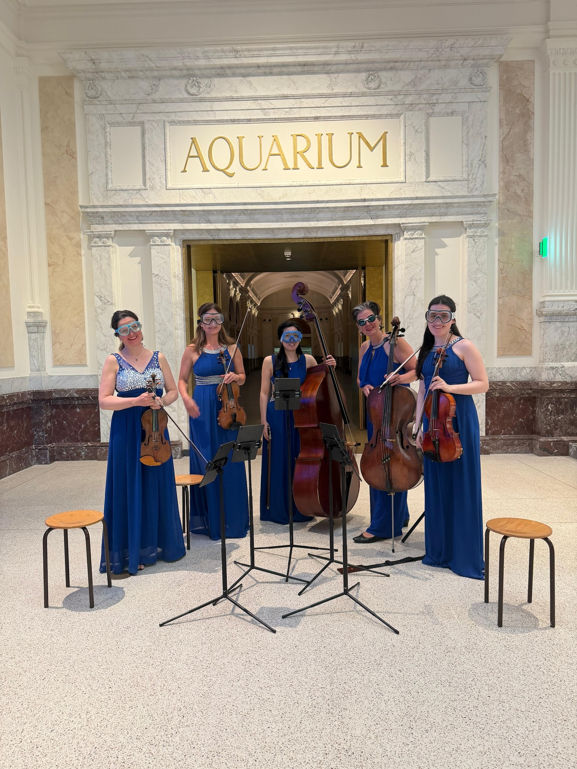 Het Strijkkwartet en contrabassist poseren met duikbrillen tijdens de opnames voor de heropening van het Aquarium in ARTIS.