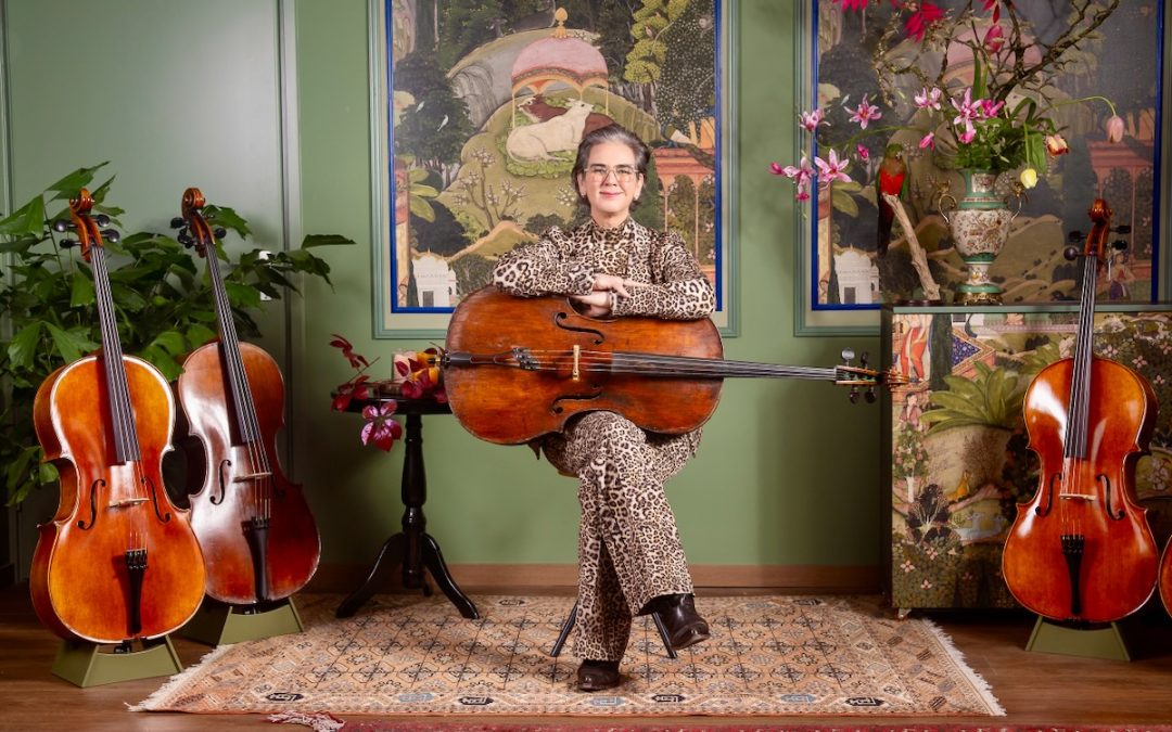 Scarlett met een oude cello in haar studio in Velp, omringd door cello’s die te koop zijn